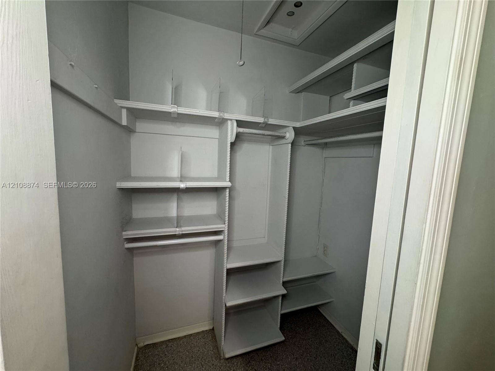 Storage closet featuring tiered built-in shelving, vertical dividers, and integrated garment rods