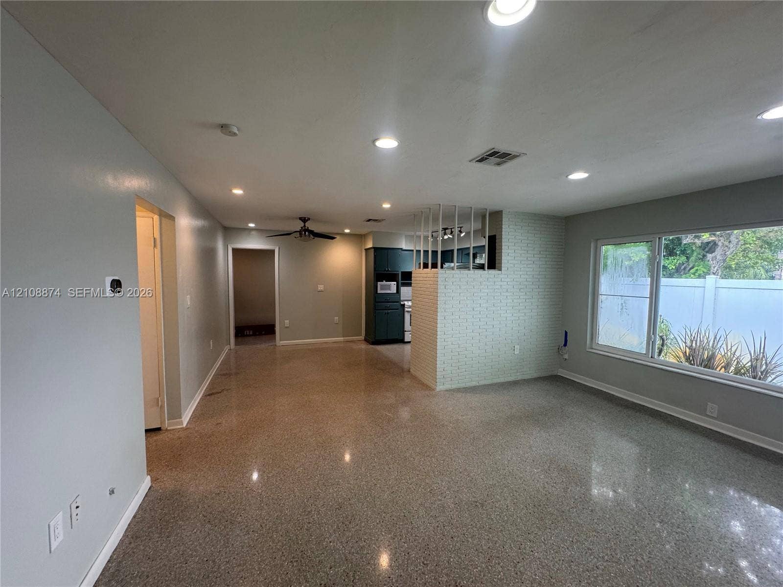 Polished aggregate flooring, recessed ceiling lighting, textured brick feature wall, and large picture window