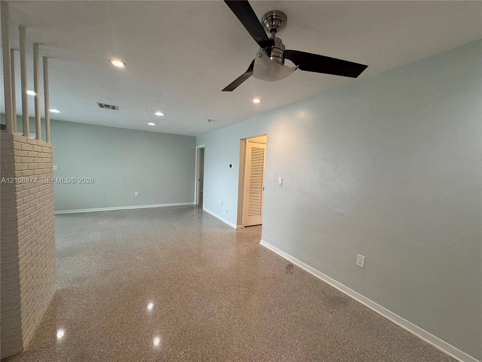 Terrazzo flooring, white painted brick accent wall, recessed lighting, and ceiling fan with integrated light fixture