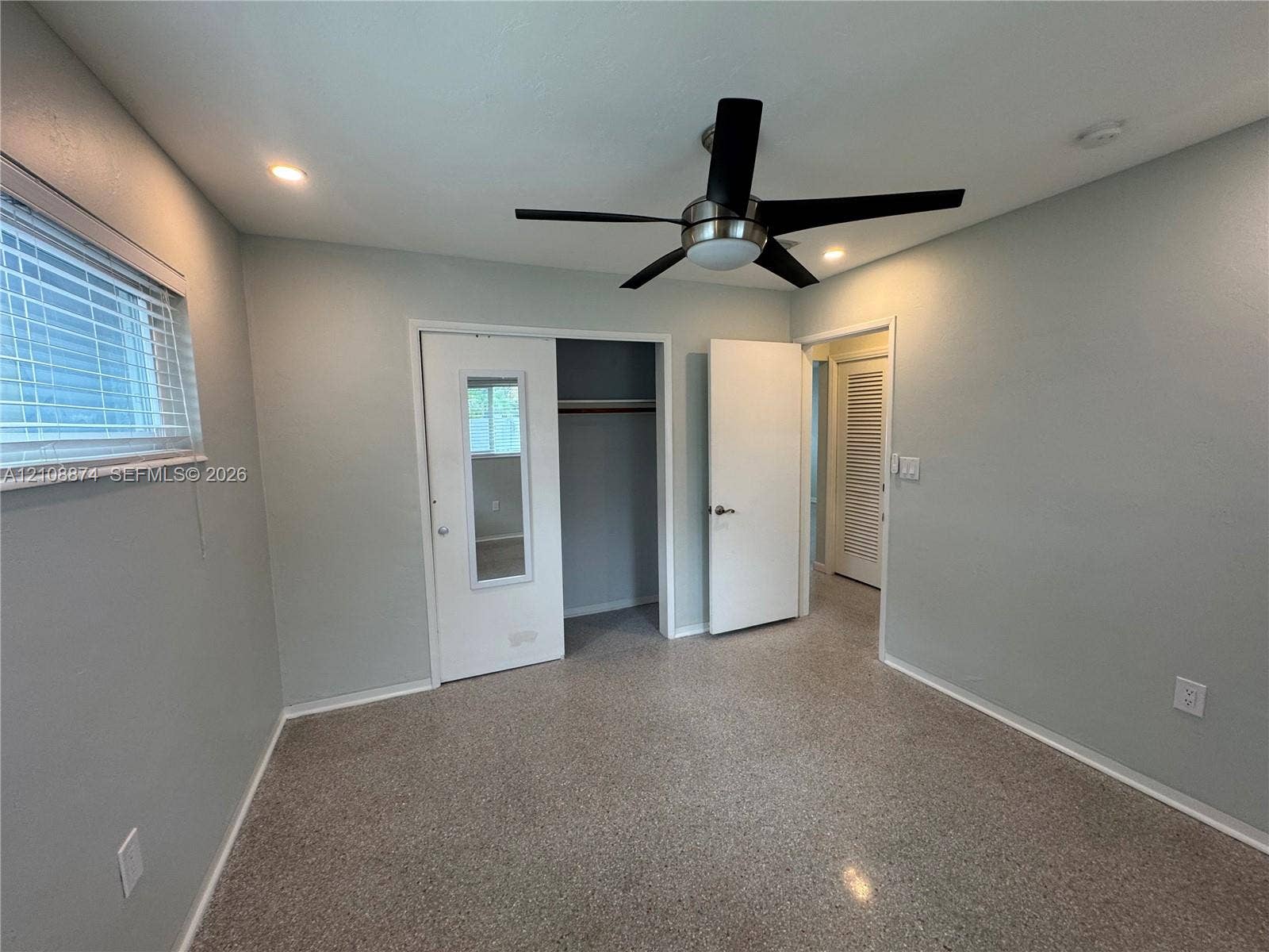 Interior space featuring stone-composite flooring, recessed lighting, a modern ceiling fan, a closet with a mirror-inset door, and louvered closet doors