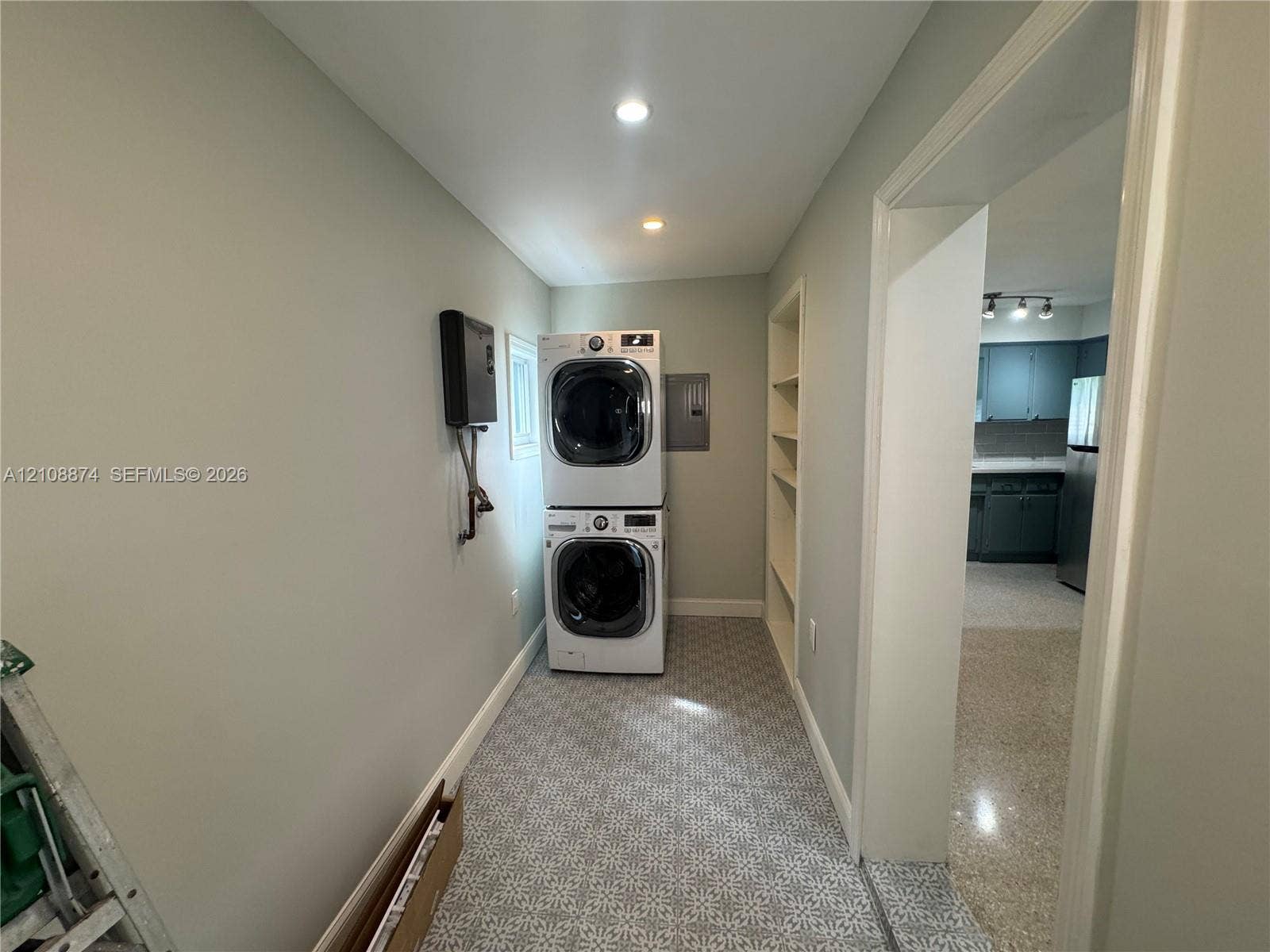 Utility space featuring patterned tile flooring, built-in recessed shelving, and recessed ceiling lighting