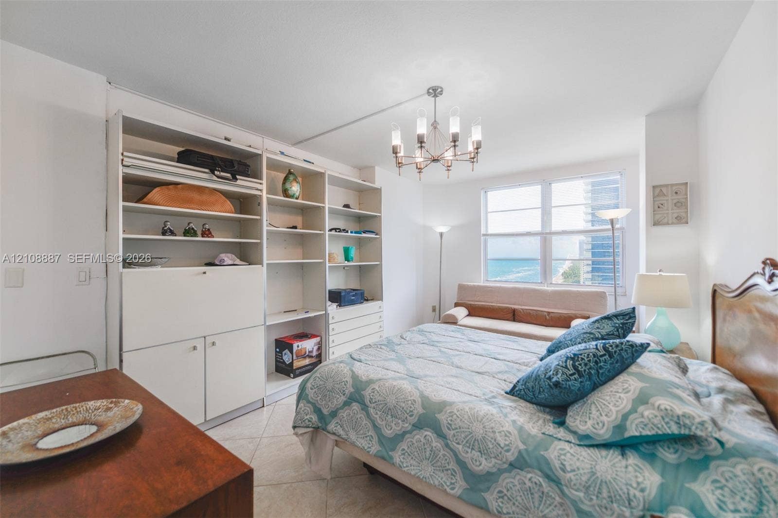 Built-in white storage cabinetry, tiled flooring, multi-pane window, and a decorative overhead light fixture