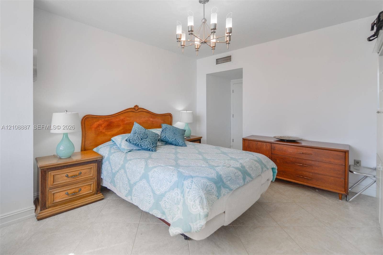 Room featuring tile flooring and a multi-arm metallic chandelier with frosted glass shades