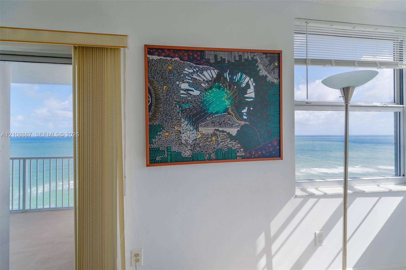 Floor-to-ceiling sliding glass doors, multi-pane window with horizontal blinds, and private balcony with metal railing, showcasing an expansive ocean horizon