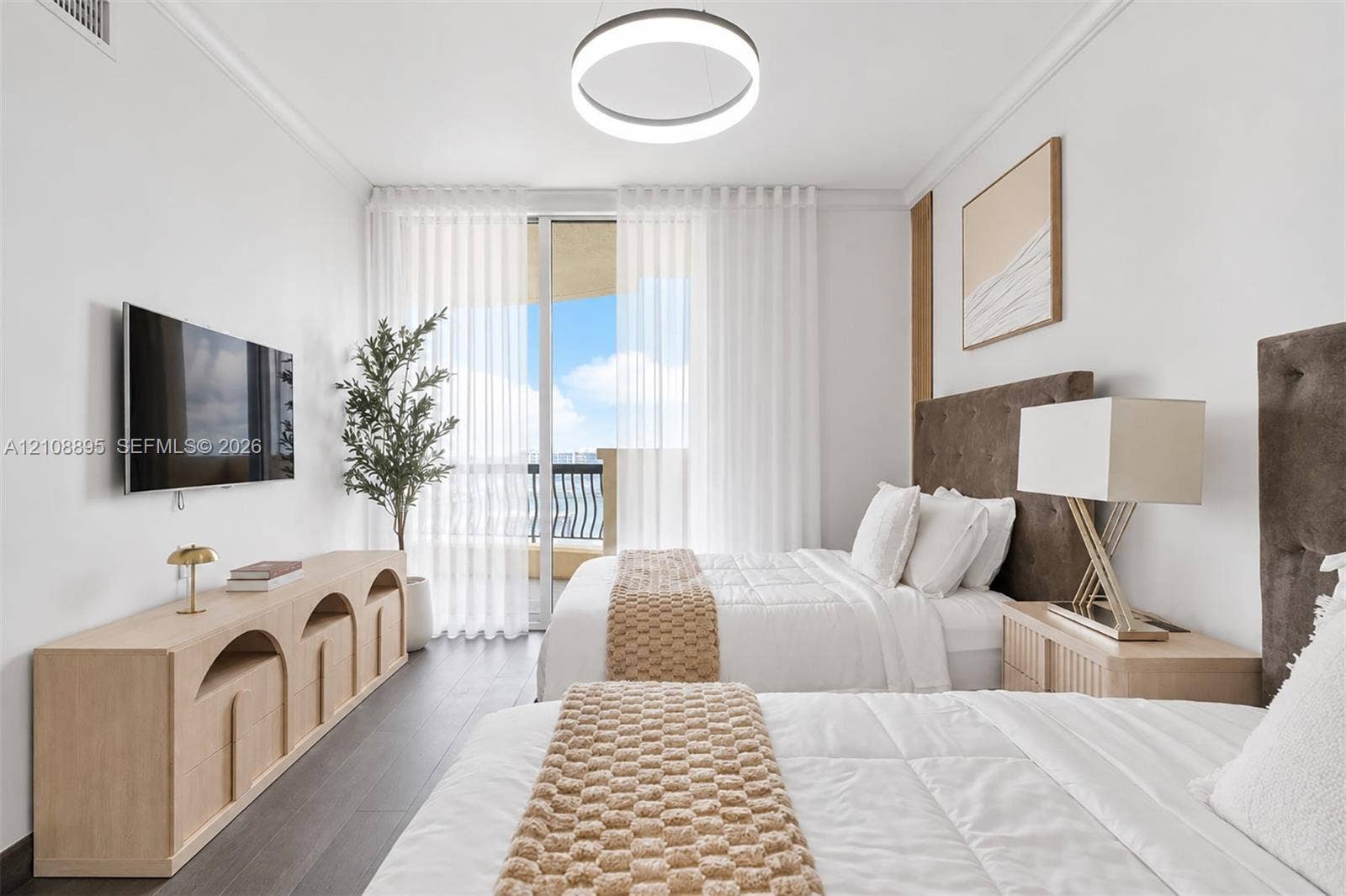 Floor-to-ceiling glass sliding doors opening to a balcony, dark wood-finish flooring, and a modern circular LED light fixture