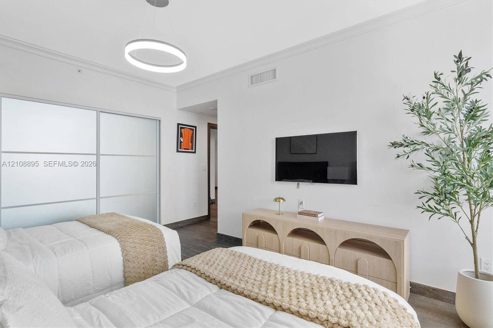 Contemporary room featuring frosted-glass sliding closet doors, circular LED pendant lighting, wood-finish flooring, and crisp white walls