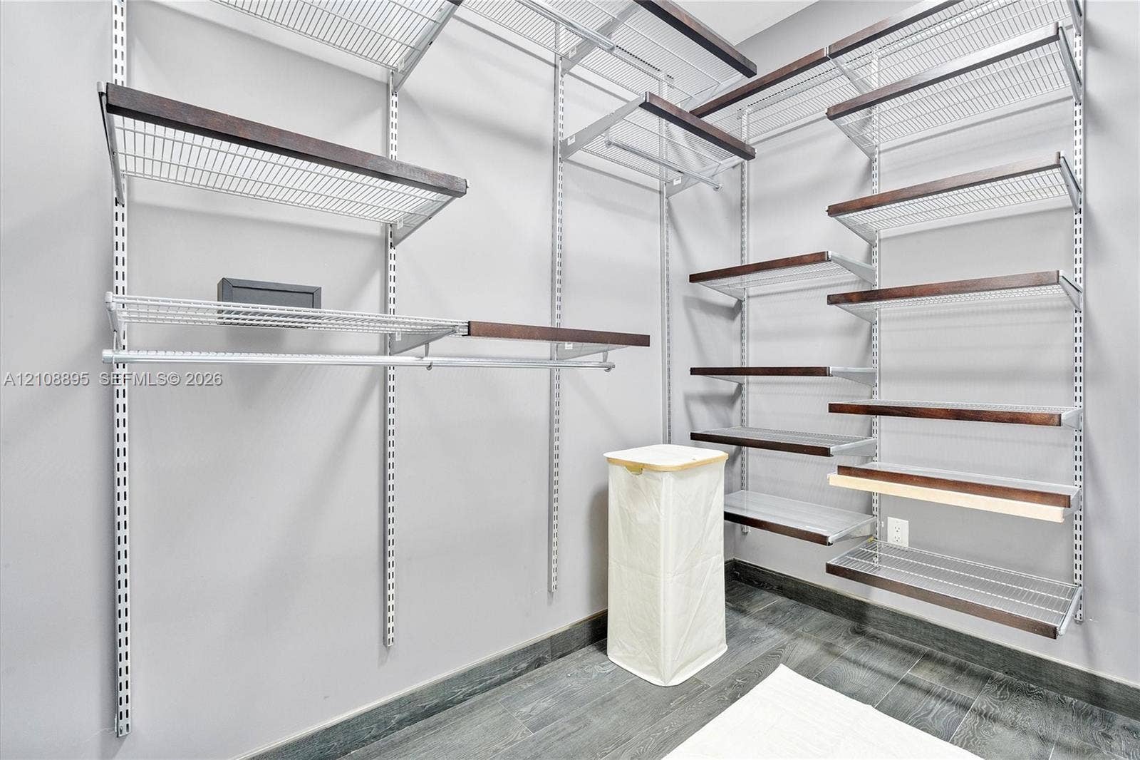 Customizable modular storage system featuring adjustable metal shelving with dark-toned wood trim and integrated hanging rods, complemented by dark wood-finish flooring