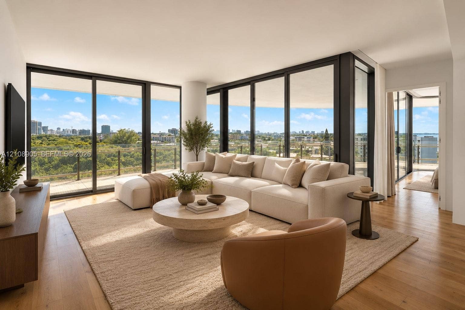 Floor-to-ceiling sliding glass walls, expansive wraparound balcony with glass railing, wood-finish flooring, and recessed ceiling lighting