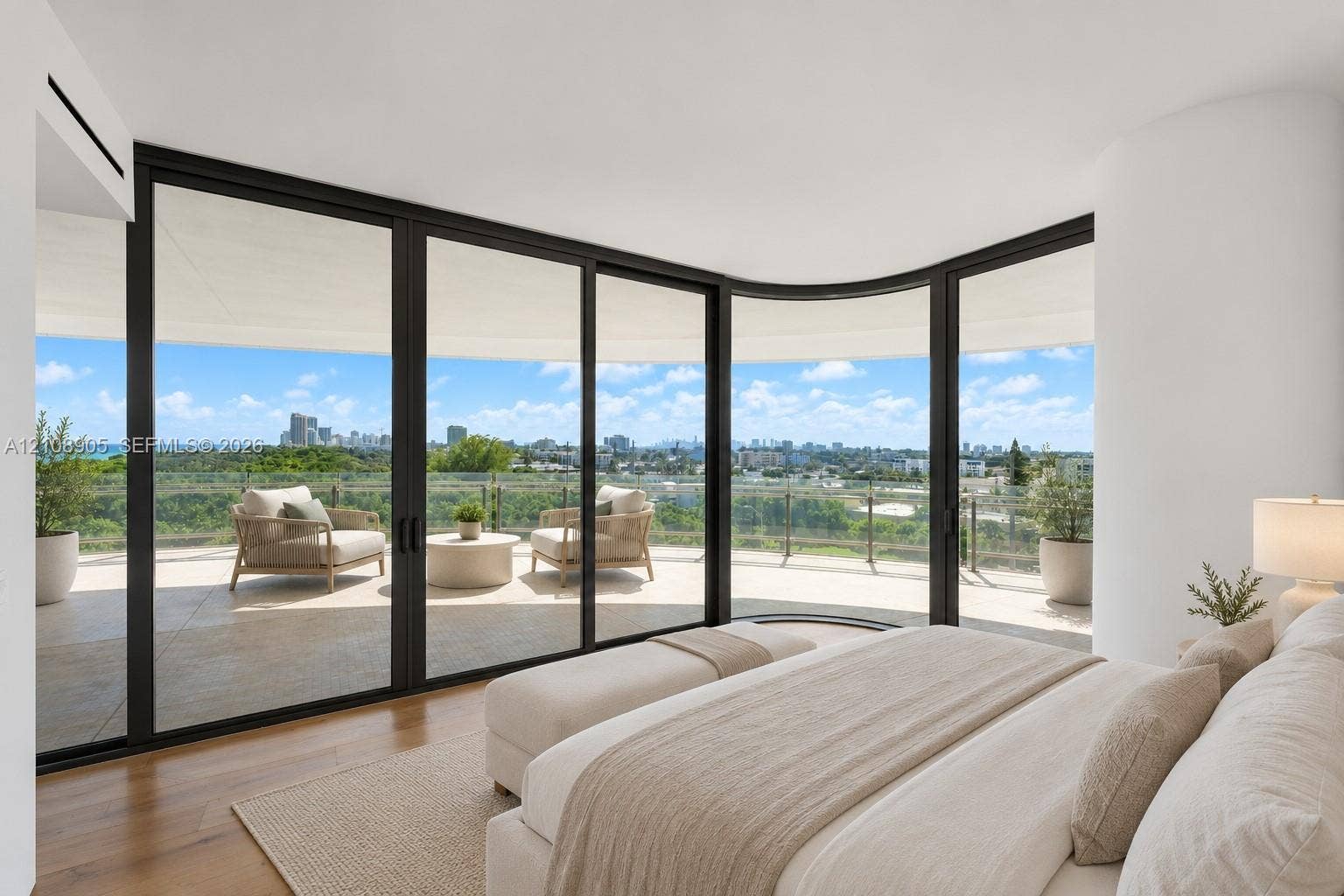 Curved floor-to-ceiling glass walls with black frames, wood-finish flooring, and a expansive wrap-around balcony featuring a glass railing