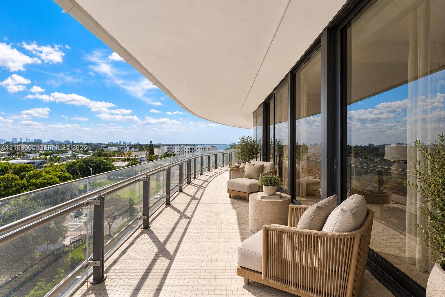 Curved balcony featuring tile flooring, glass panel railing with metal posts, and floor-to-ceiling glass wall