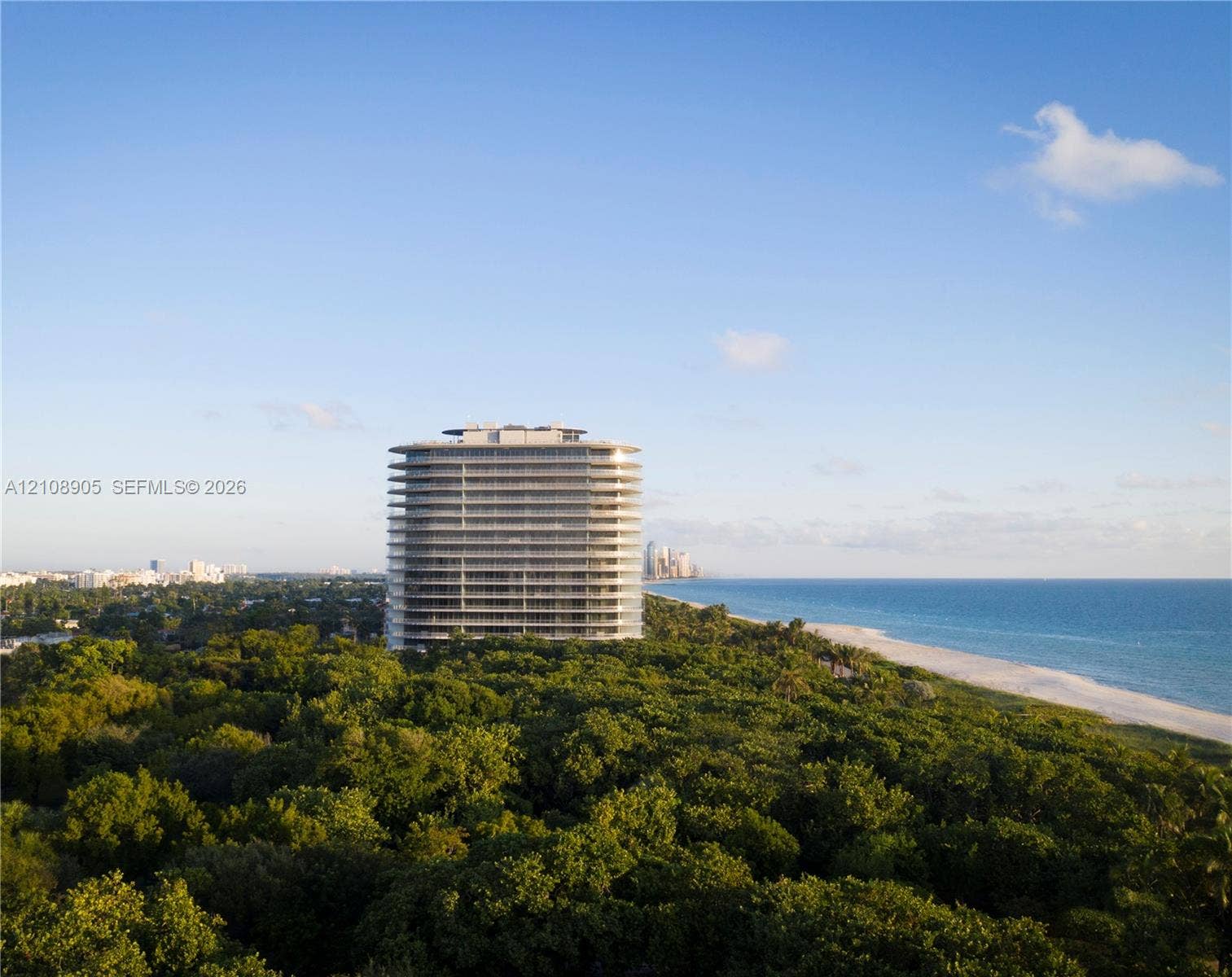 High-rise residential building featuring wraparound balconies, floor-to-ceiling glass paneling, and direct coastal proximity