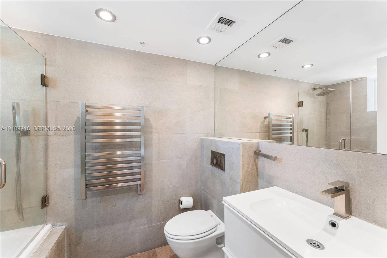 Beautifully remodeled master bathroom featuring a heated towel rack and a luxurious bathtub with a rainfall shower-head and convenient handheld shower for a spa-like experience.