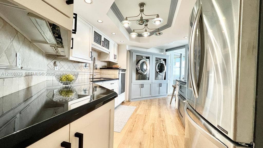 Kitchen featuring solid-surface countertops, recessed ceiling lighting, wood-finish flooring, built-in cabinetry, and integrated laundry appliances