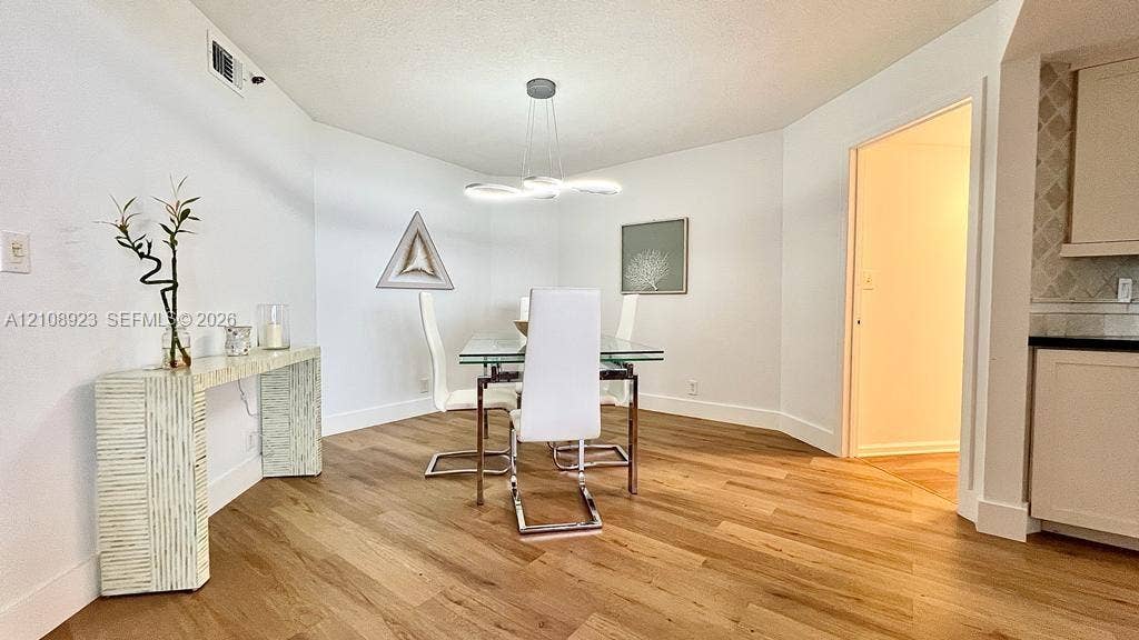 Dining area featuring wood-finish flooring, modern multi-ring LED chandelier, and recessed ceiling lighting