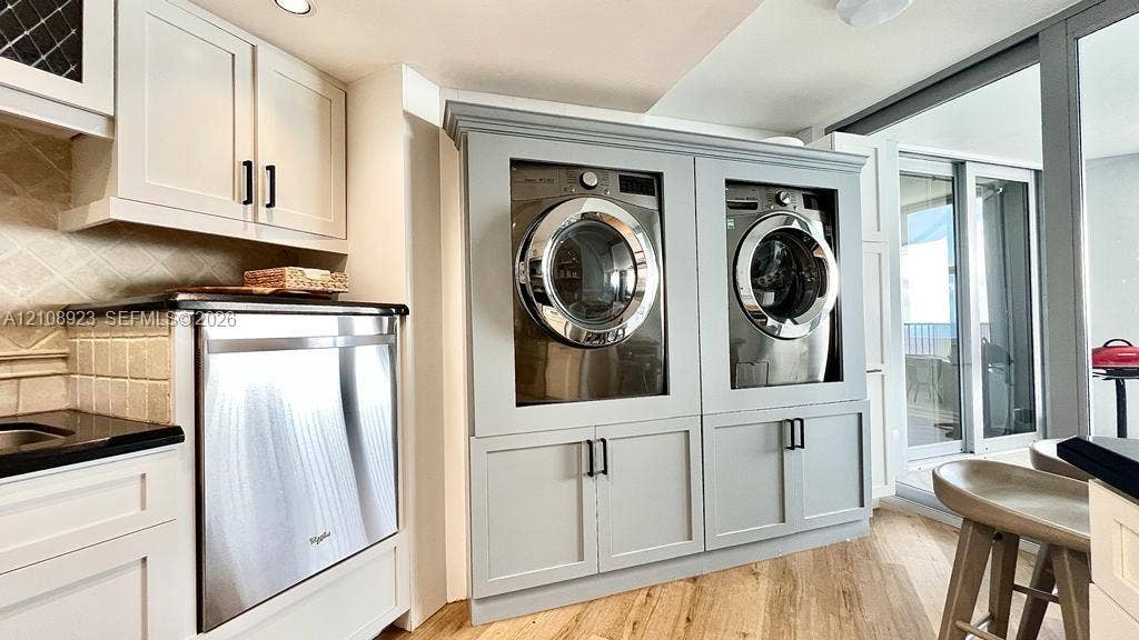 Built-in laundry cabinetry with integrated stainless steel appliances, neutral wood-finish flooring, and recessed ceiling lighting