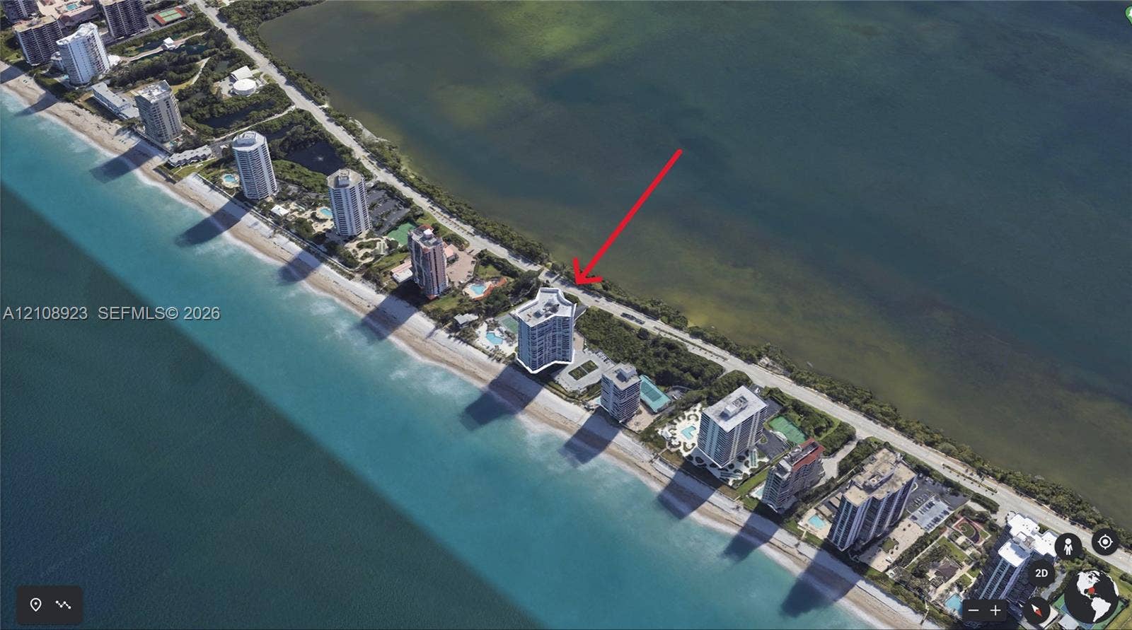 Aerial perspective of coastal high-rise property featuring direct beachfront access, structured parking, and an outdoor swimming pool