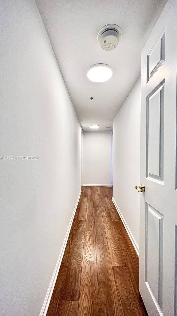 Hallway featuring wood-finish flooring, white walls, and flush-mount ceiling lighting