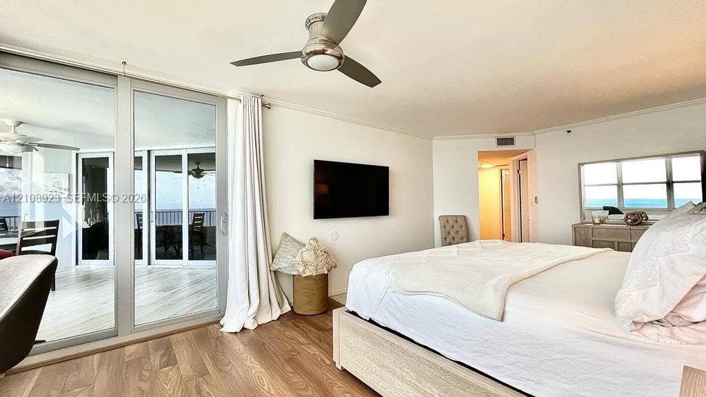Wood-finish flooring, floor-to-ceiling sliding glass doors, brushed nickel ceiling fan with integrated lighting, and horizontal sliding window