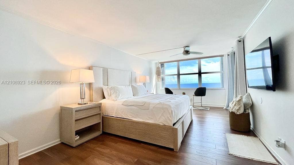 Wood-finish flooring, floor-to-ceiling windows with ocean exposure, and a modern ceiling fan