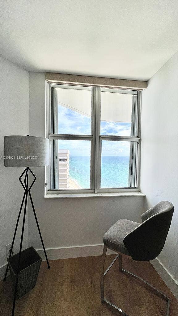 Double-pane sliding window with neutral trim, wood-finish flooring, and coastal scenery
