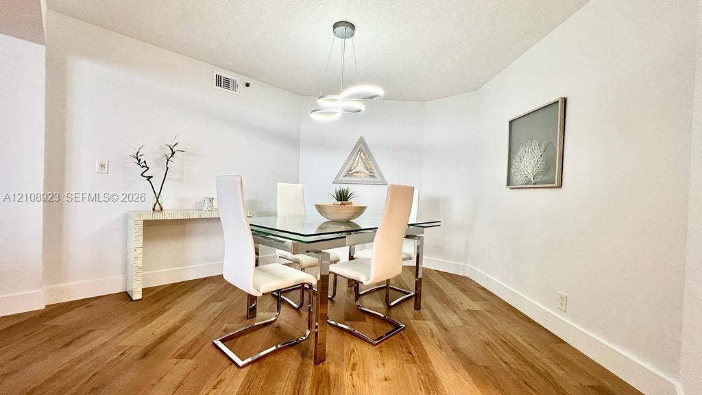Dining area featuring wood-finish flooring and a multi-ring LED pendant light fixture