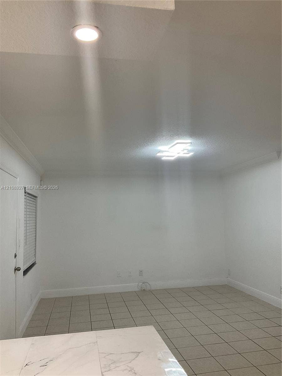 Neutral interior space featuring ceramic tile flooring, modern flush-mount geometric ceiling lighting, recessed lighting, and a white interior door with a blind-fitted window