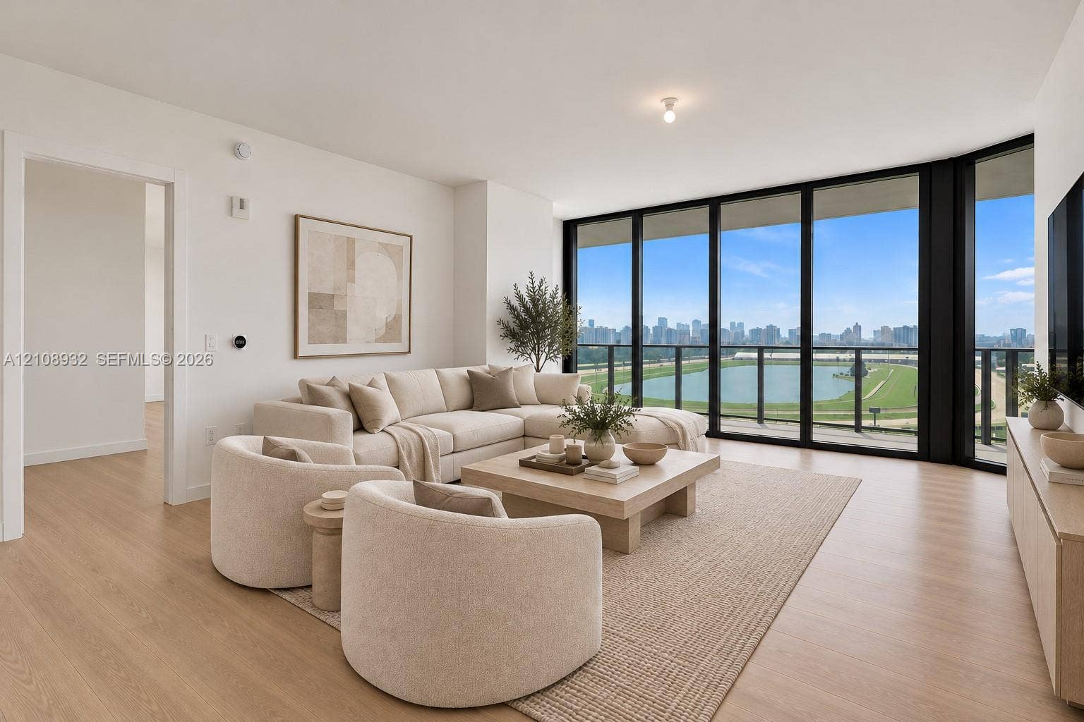1170 E Hallandale Beach Boulevard, #1201, Hallandale Beach, FL 33009 Floor-to-ceiling black-framed windows, wood-finish flooring, and balcony access showcasing water and urban scenery
