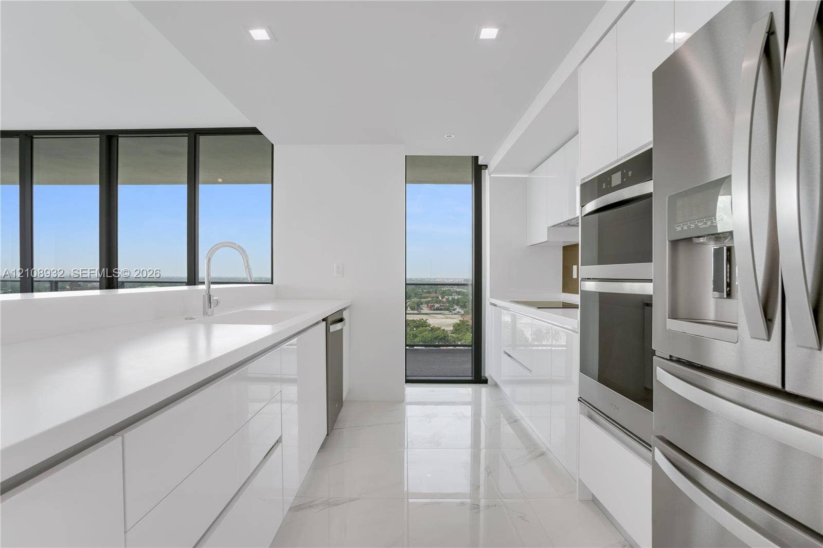 1170 E Hallandale Beach Boulevard, #1201, Hallandale Beach, FL 33009 Kitchen featuring white gloss cabinetry, expansive solid-surface countertops, stainless steel double wall ovens, high-gloss tile flooring, and floor-to-ceiling windows