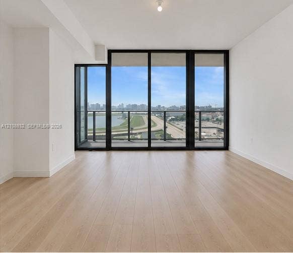 1170 E Hallandale Beach Boulevard, #1201, Hallandale Beach, FL 33009 Floor-to-ceiling windows with black frames, wood-finish flooring, and a glass-railing balcony