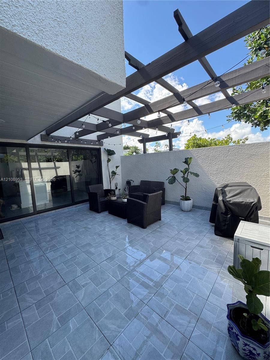 Outdoor patio featuring large-format ceramic tiling, a custom wood-beam pergola, and expansive sliding glass doors
