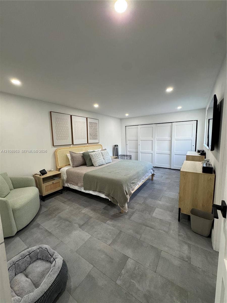 Large-format gray tile flooring, recessed ceiling lighting, and sliding multi-panel closet doors