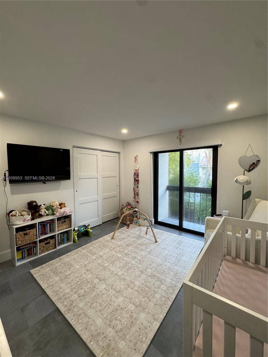 Interior room featuring dark tile flooring, sliding glass door with a black frame, and two-panel closet doors