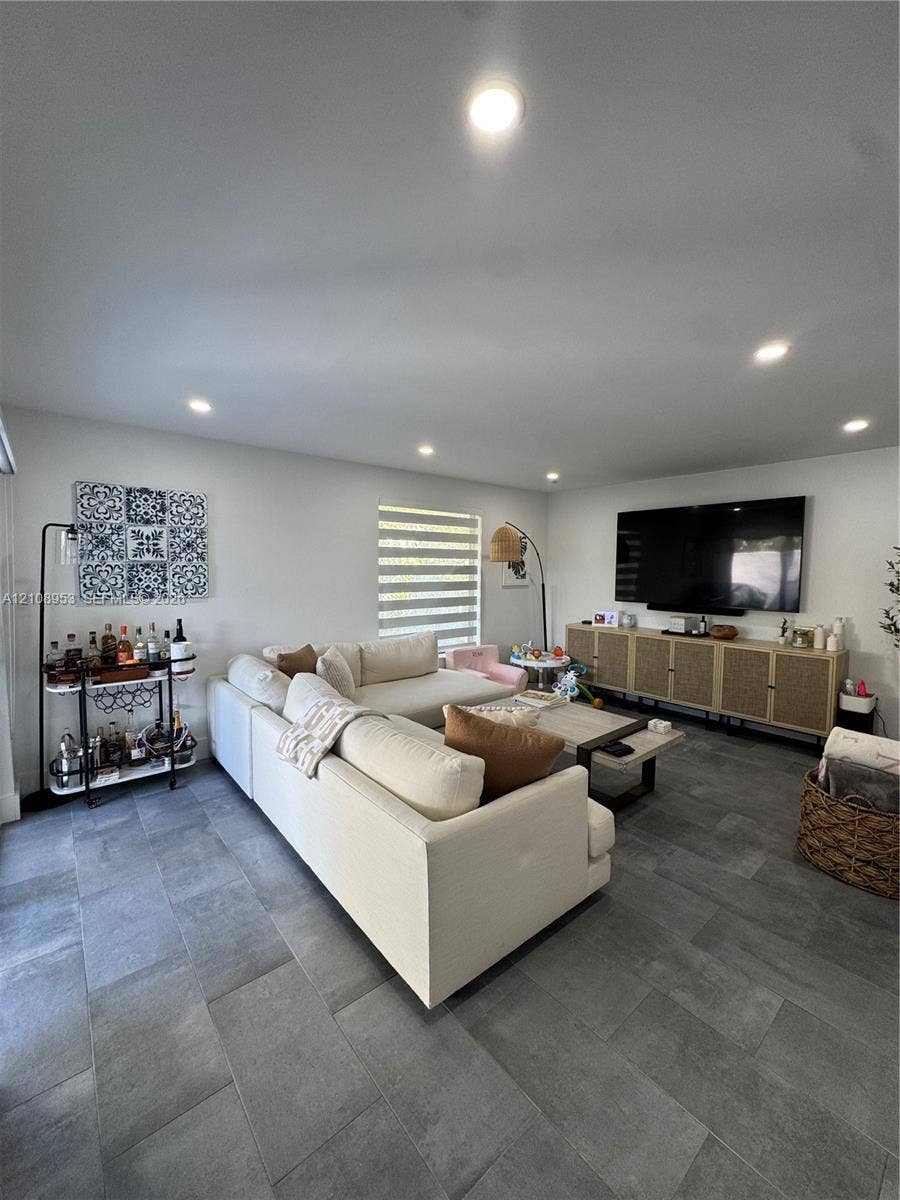 Living area featuring large-format tile flooring, recessed lighting, and a neutral color palette