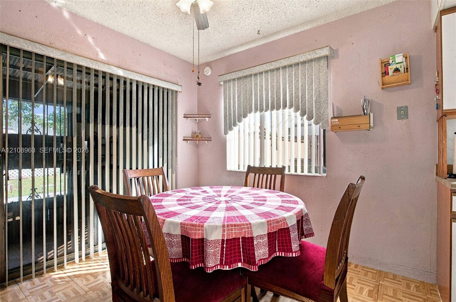 Sliding glass door, window with vertical blinds, parquet flooring, and ceiling-mounted light fixture