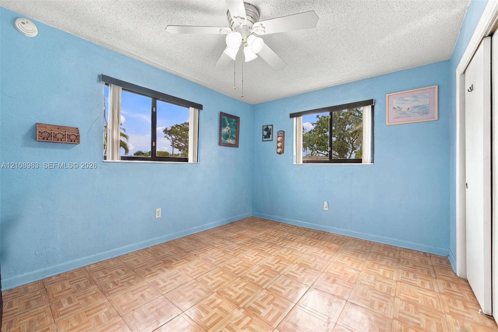 Interior room featuring parquet flooring, dual windows, and a ceiling-mounted light fixture with a fan