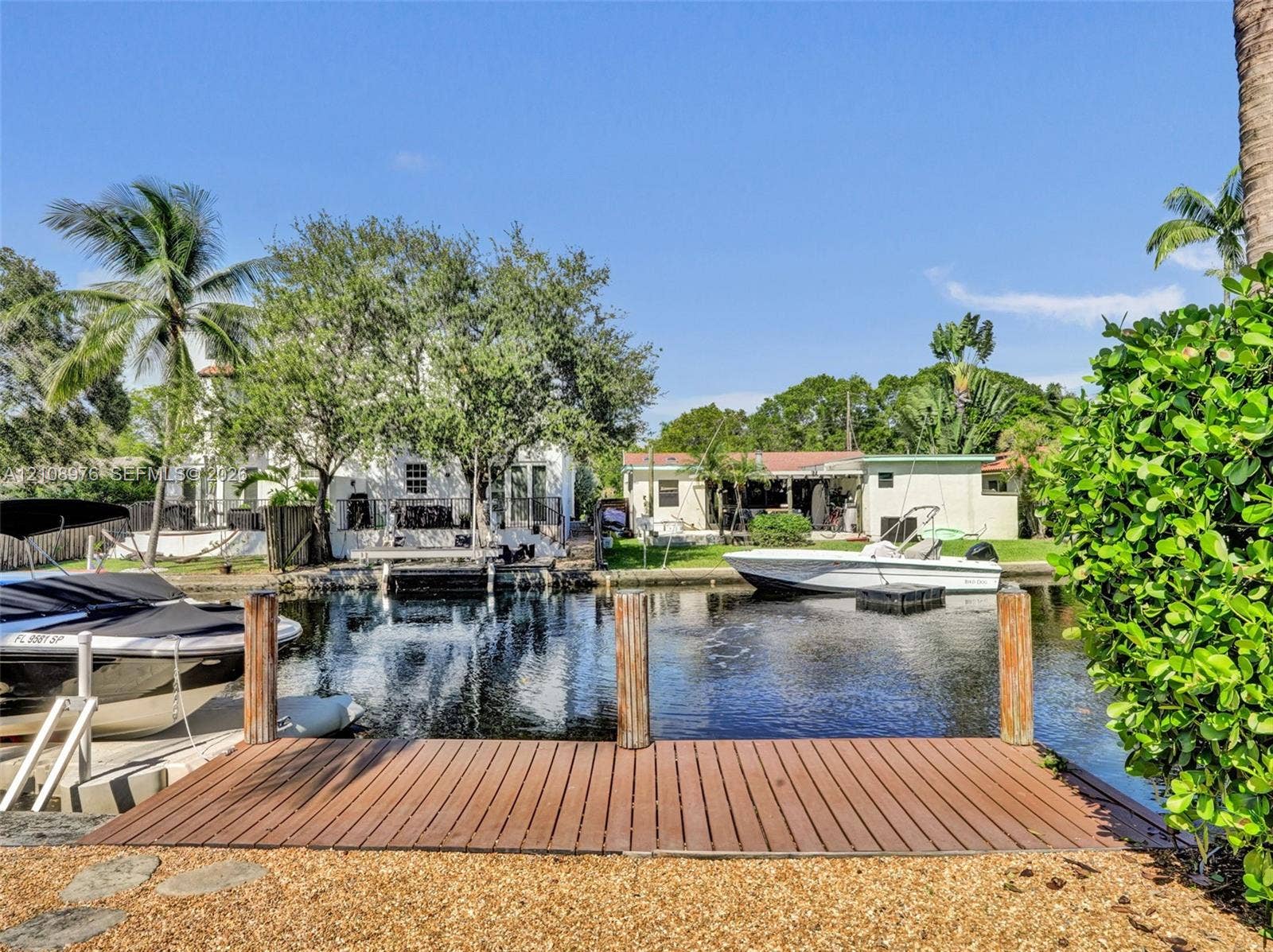 525 SW 12th Street, Fort Lauderdale, Fort Lauderdale, FL 33315 Waterfront canal property featuring a wooden boat dock, mature landscaping, and structural seawall