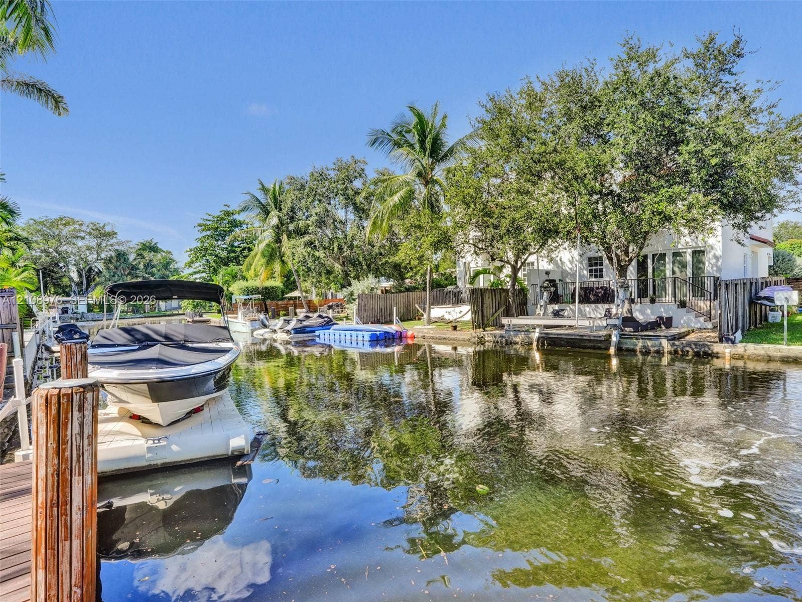 525 SW 12th Street, Fort Lauderdale, Fort Lauderdale, FL 33315 Waterfront property featuring a private boat lift, concrete bulkhead, mature trees, and direct canal access