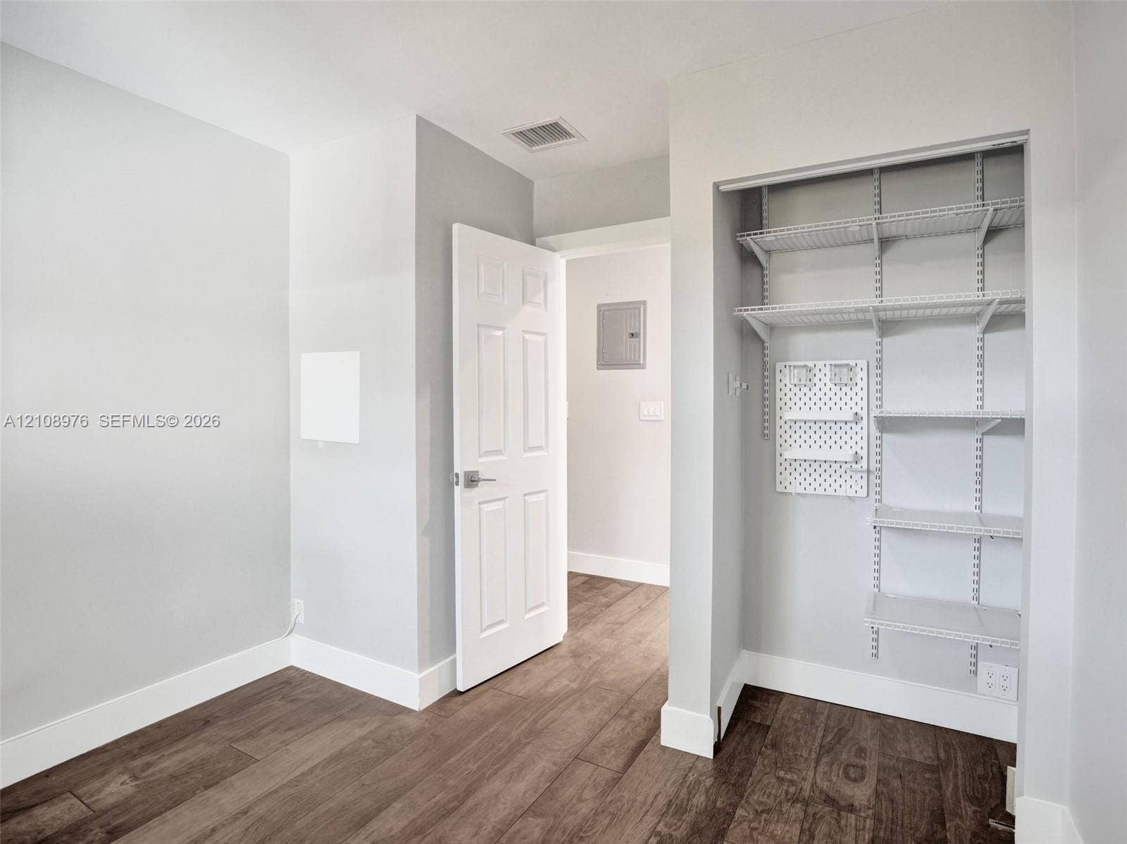 525 SW 12th Street, Fort Lauderdale, Fort Lauderdale, FL 33315 Bedroom 3. Wood-finish flooring featuring a built-in closet with adjustable wire shelving and a wall-mounted pegboard organizer
