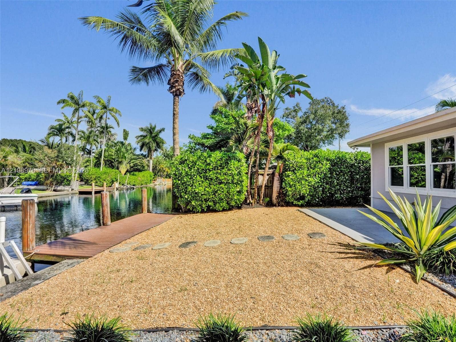 525 SW 12th Street, Fort Lauderdale, Fort Lauderdale, FL 33315 Waterfront property featuring a private dock, graveled outdoor space, concrete patio, and mature landscaping