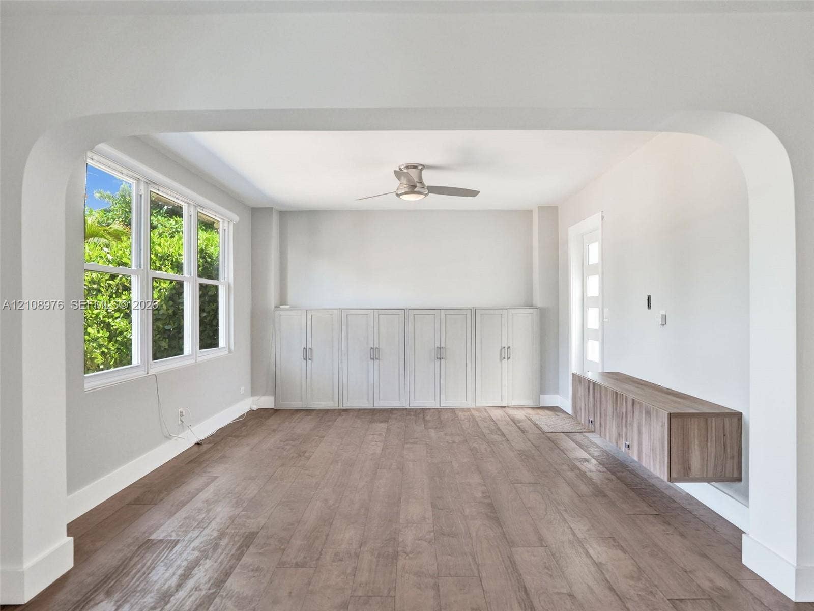 525 SW 12th Street, Fort Lauderdale, Fort Lauderdale, FL 33315 Architectural archway, wood-finish flooring, full-wall built-in cabinetry, wall-mounted floating console, and ceiling fan with integrated lighting