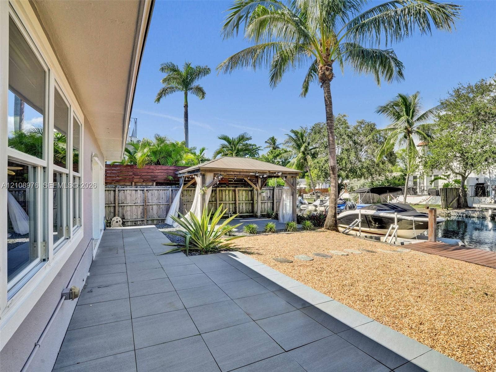 525 SW 12th Street, Fort Lauderdale, Fort Lauderdale, FL 33315 Rear outdoor area featuring a stone-tile patio, a gravel landscape, a wooden pergola, and a private dock