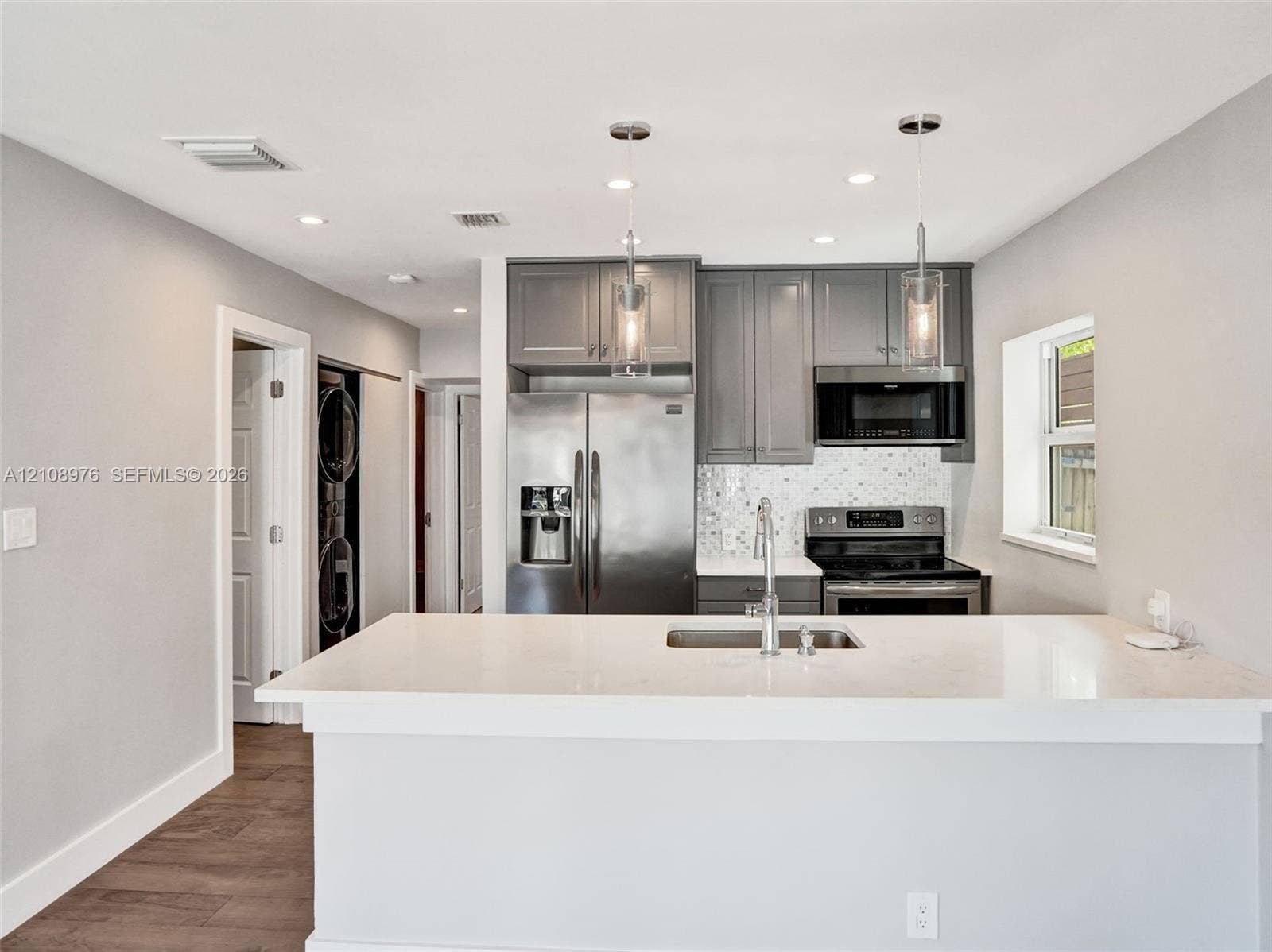 525 SW 12th Street, Fort Lauderdale, Fort Lauderdale, FL 33315 Kitchen featuring gray cabinetry, stainless steel appliances, white quartz countertops, mosaic tile backsplash, and dual pendant lighting