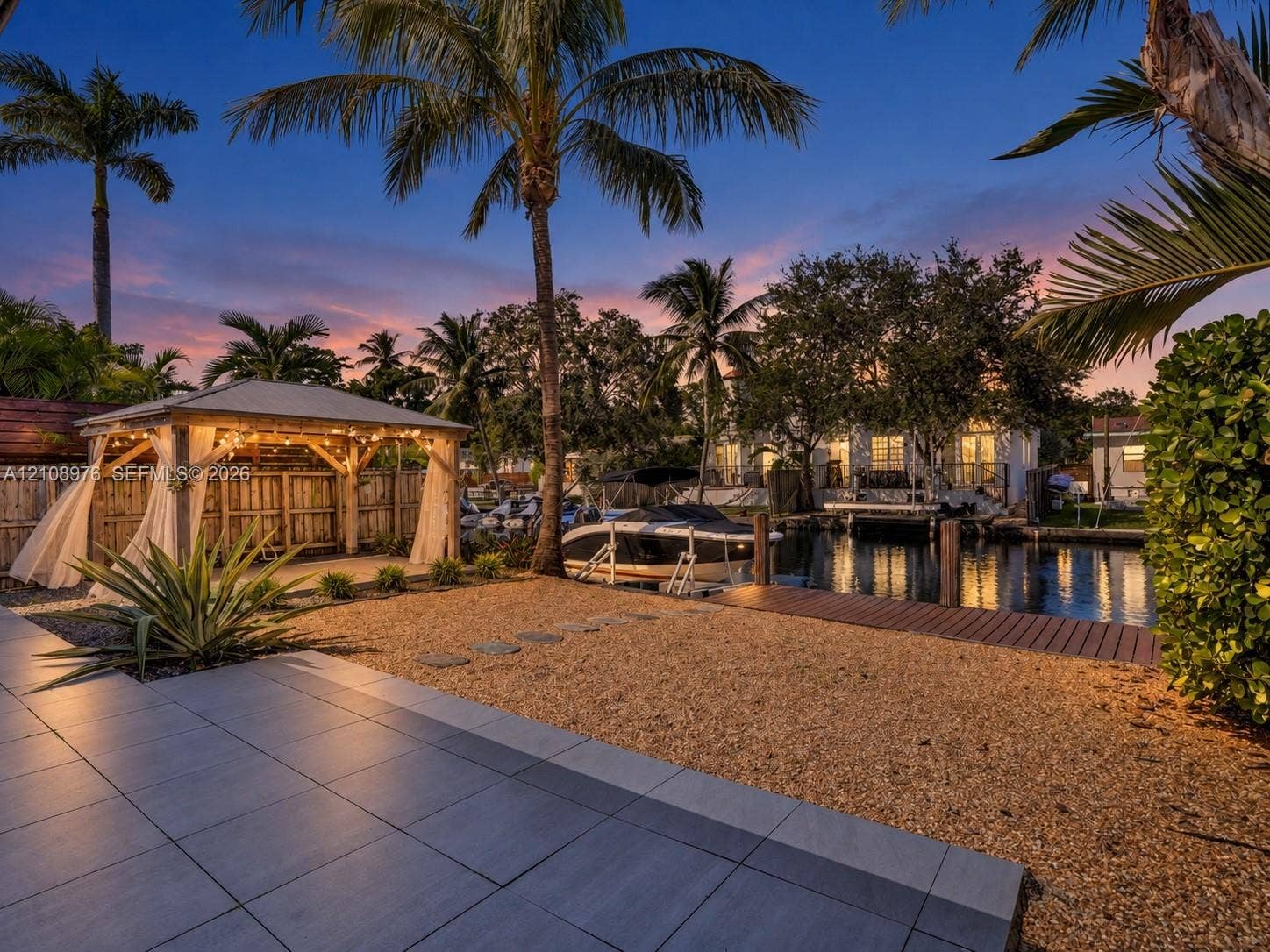 525 SW 12th Street, Fort Lauderdale, Fort Lauderdale, FL 33315 Waterfront property featuring a covered timber-framed gazebo, wooden dock, gravel landscaping, and large-format tile patio