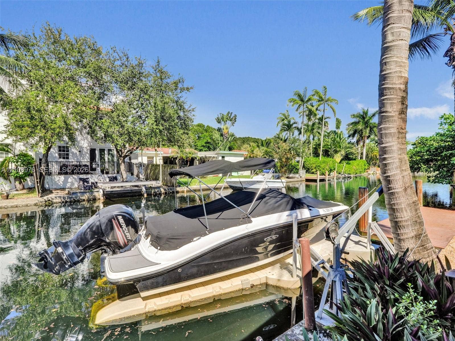 525 SW 12th Street, Fort Lauderdale, Fort Lauderdale, FL 33315 Waterfront bulkhead featuring a boat lift, concrete seawall, and tropical landscaping