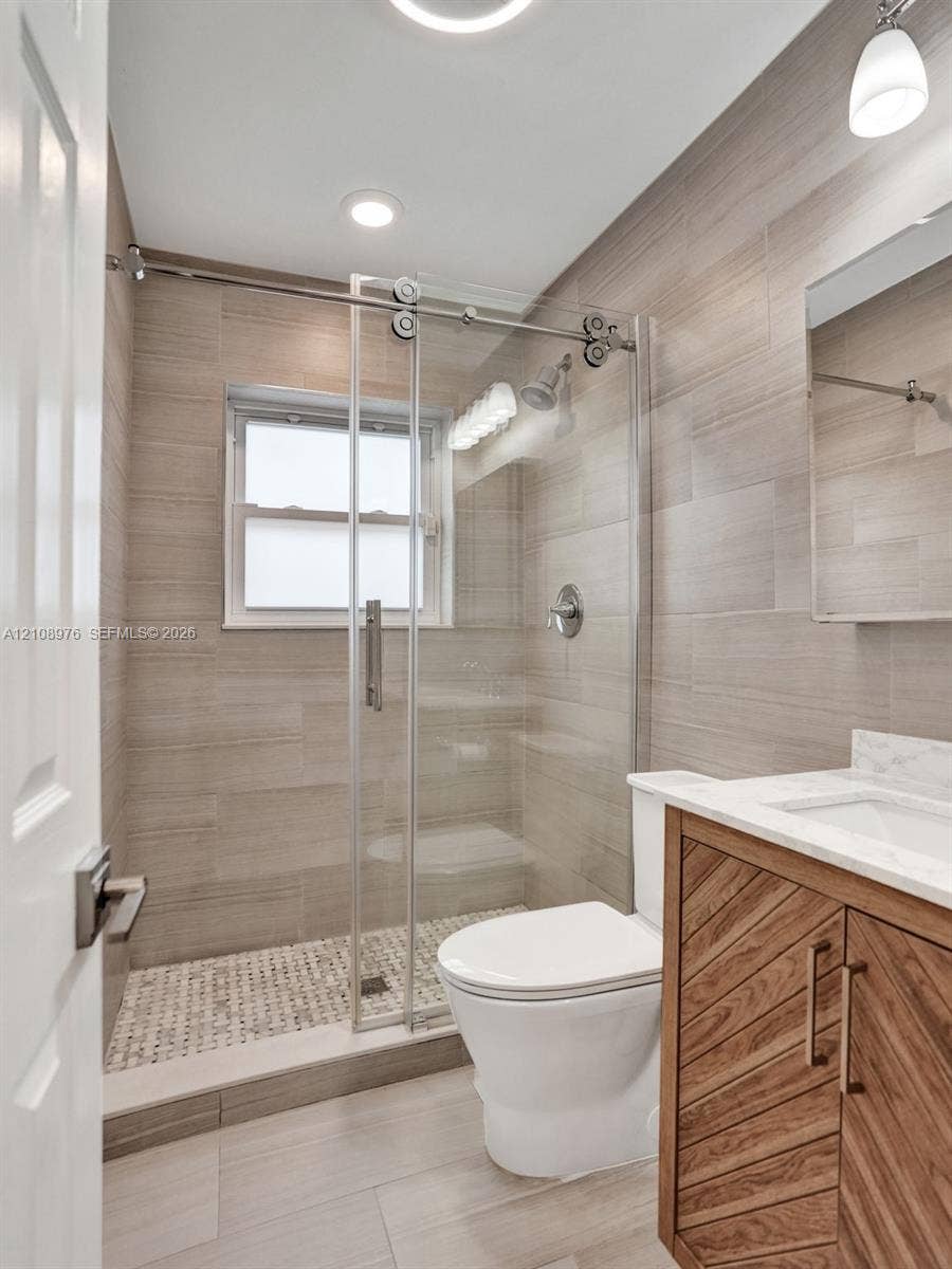 525 SW 12th Street, Fort Lauderdale, Fort Lauderdale, FL 33315 Bathroom featuring a walk-in shower with sliding glass door, linear tile surround, and pebble-style floor