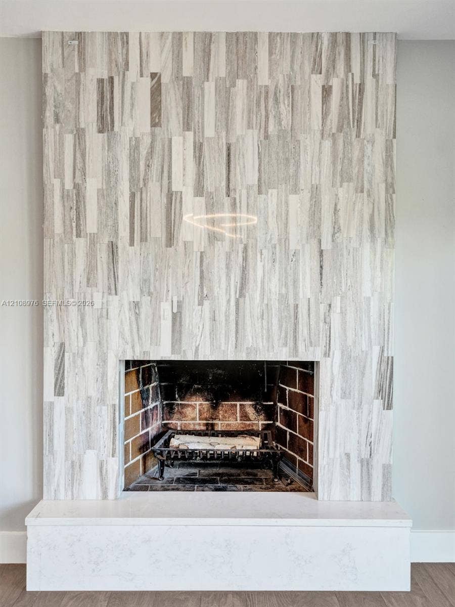 525 SW 12th Street, Fort Lauderdale, Fort Lauderdale, FL 33315 Fireplace featuring floor-to-ceiling vertical tile surround, brick-lined firebox, metal grate, and a solid rectangular hearth