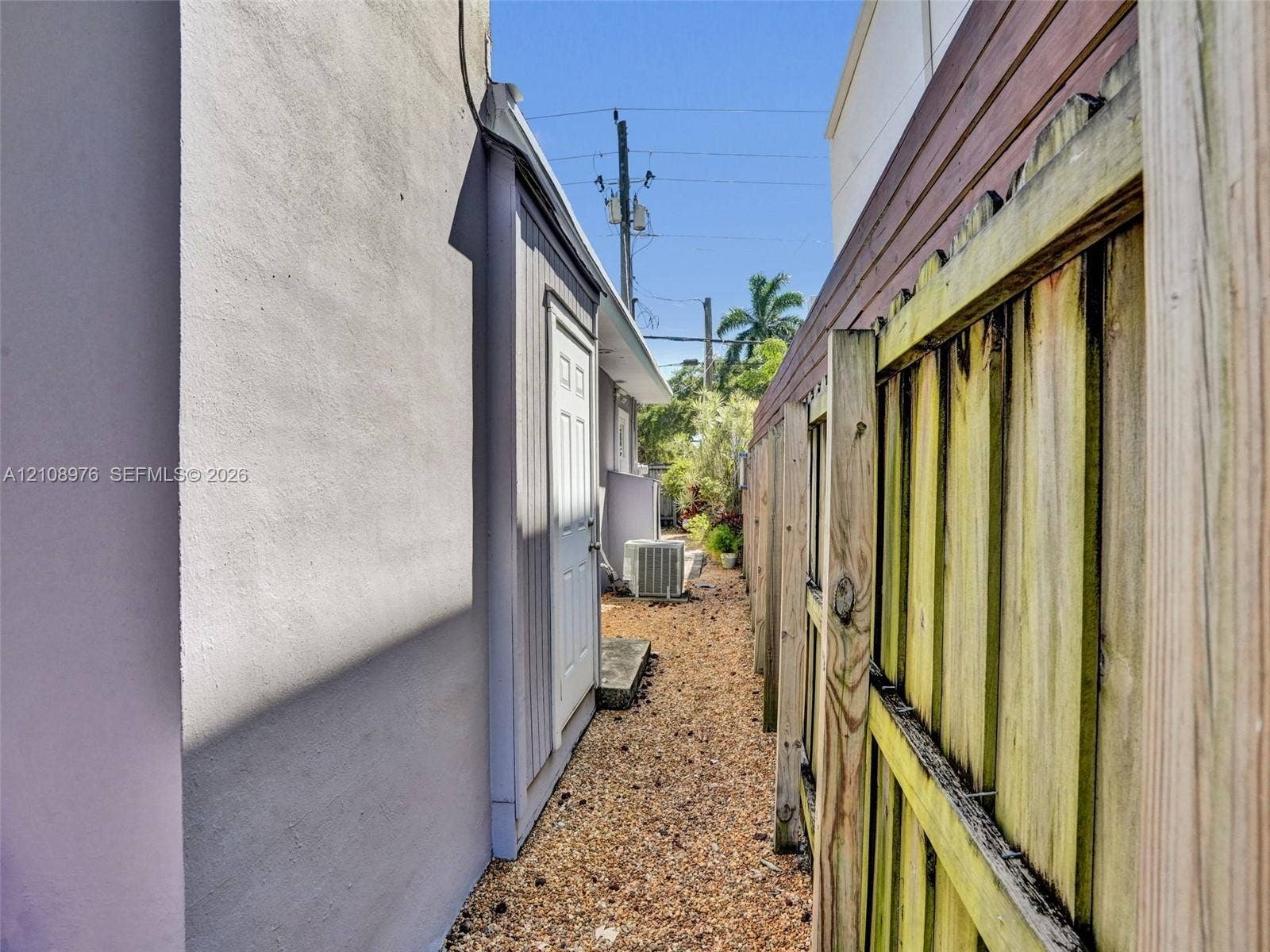 525 SW 12th Street, Fort Lauderdale, Fort Lauderdale, FL 33315 Side exterior area featuring a concrete pathway, gravel ground cover, and wood privacy fencing