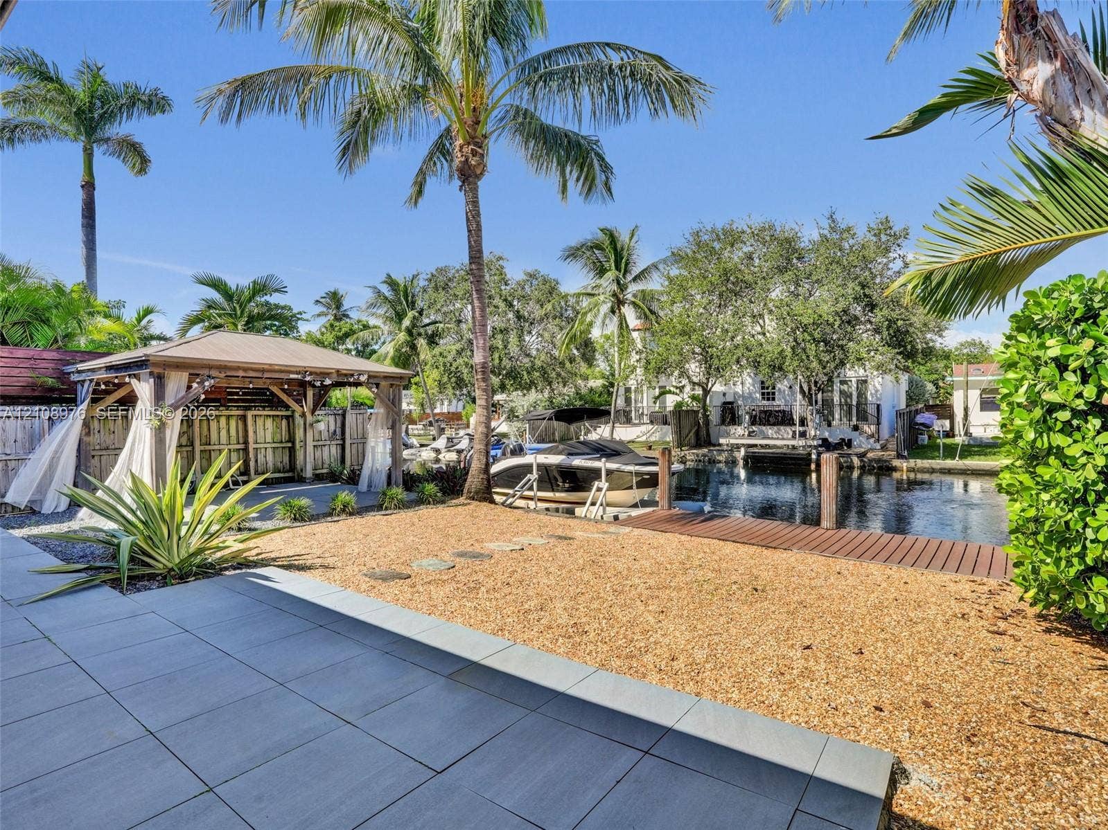 525 SW 12th Street, Fort Lauderdale, Fort Lauderdale, FL 33315 Waterfront grounds featuring a permanent timber-frame gazebo, with space for a summer kitchen and living are, a private dock, gravel hardscaping, and large-format porcelain patio tiling