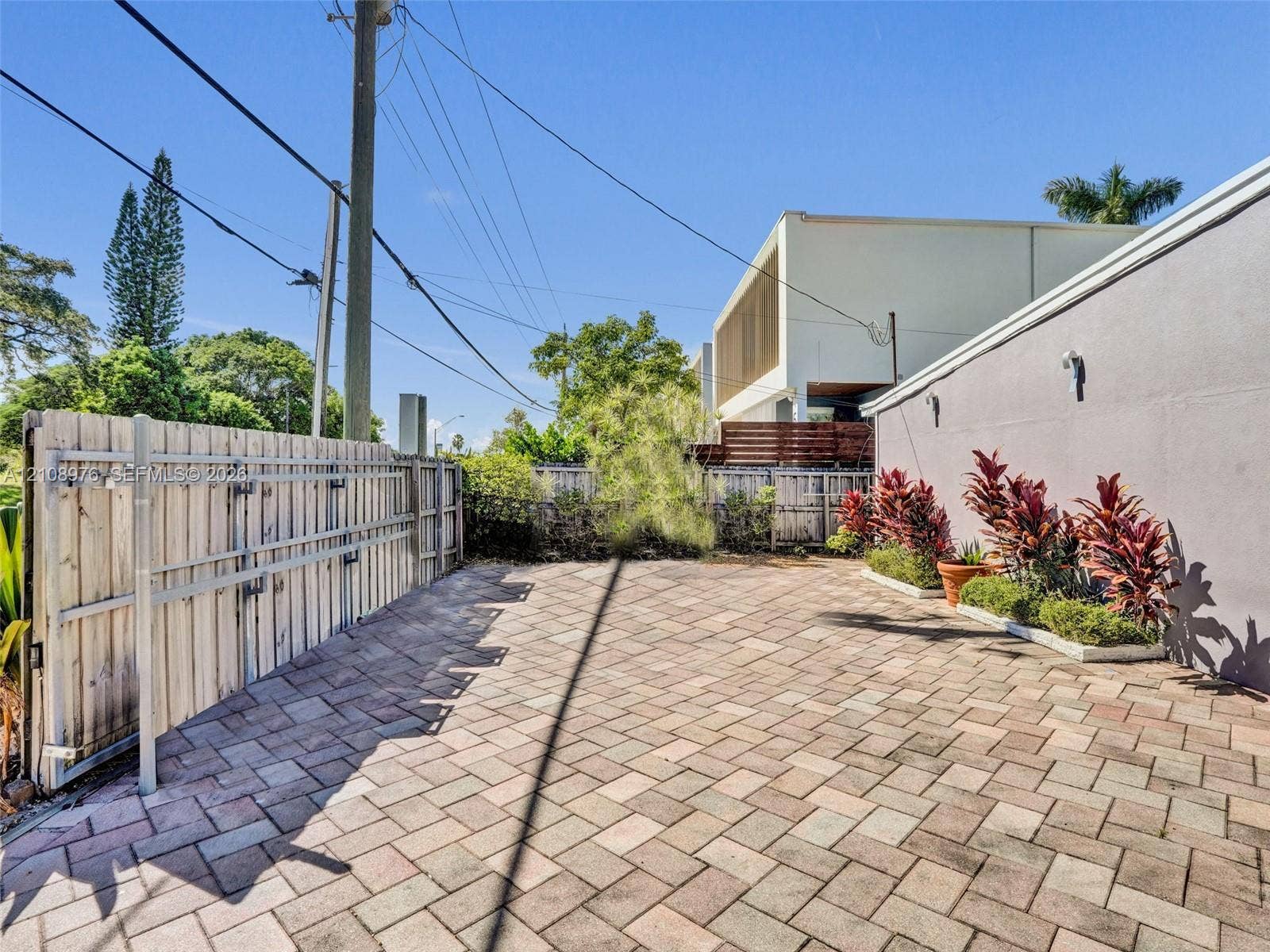 525 SW 12th Street, Fort Lauderdale, Fort Lauderdale, FL 33315 Paved courtyard featuring herringbone-patterned stone pavers, perimeter wood privacy fencing, and a dedicated planting bed