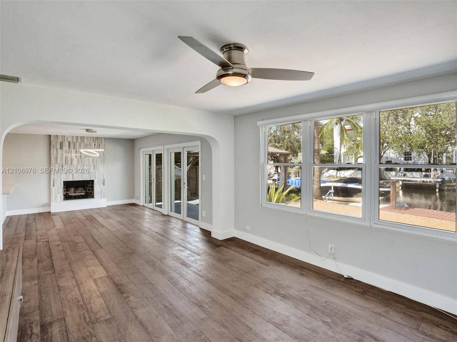 525 SW 12th Street, Fort Lauderdale, Fort Lauderdale, FL 33315 Wood-finish flooring, fireplace with vertical tile surround, recessed ceiling fan with integrated lighting, and multiple windows with water frontage